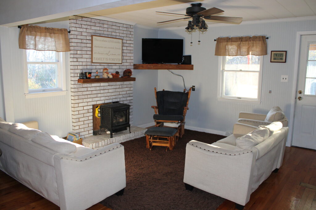After photo of a living room renovation update. Painting wood paneling and brick fireplace.