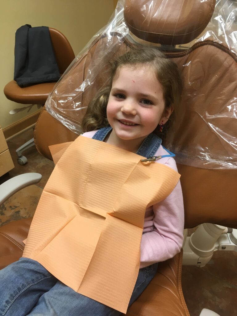 5 year old girl smiling in the dentist chair.