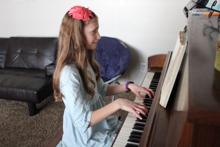 10 year old girl plays the piano at home.