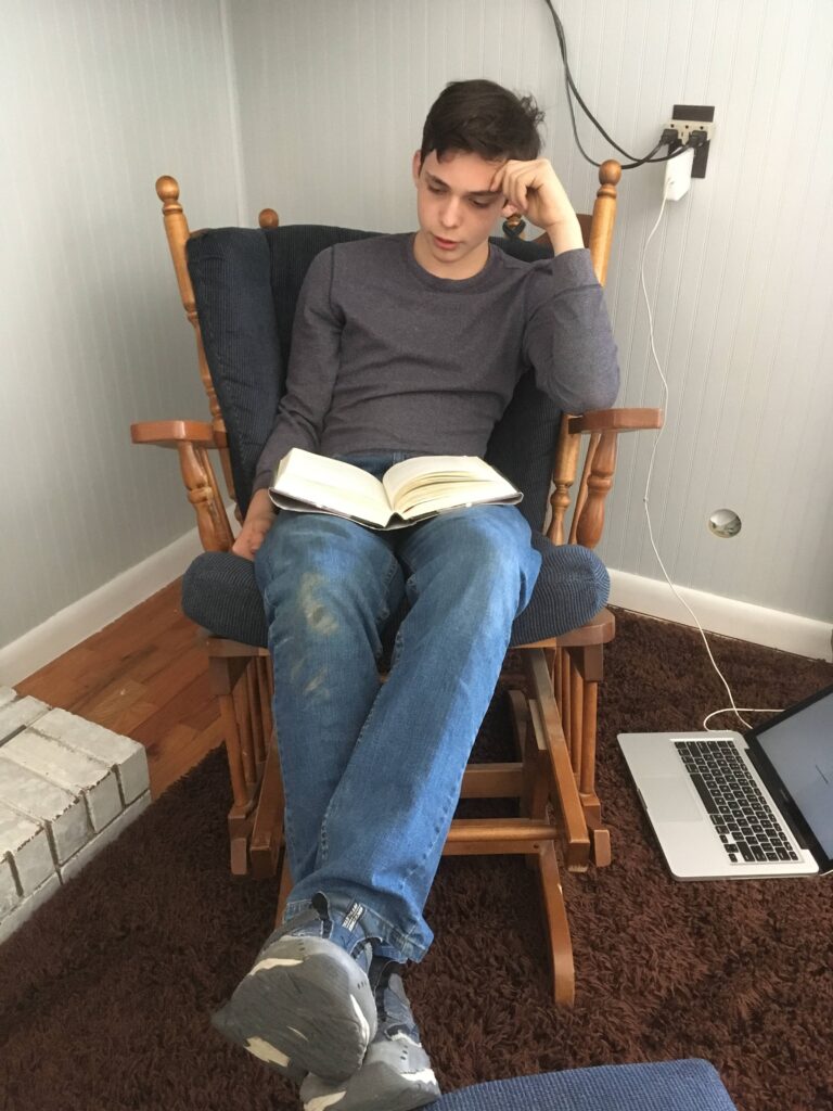 Teen boy reads in a rocker glider chair