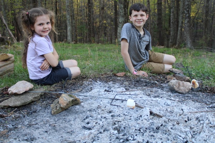 two kids roast marshmallows with rocks propping up their sticks