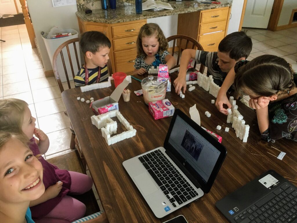 6 children make castles out of sugar cubes for a homeschool activity