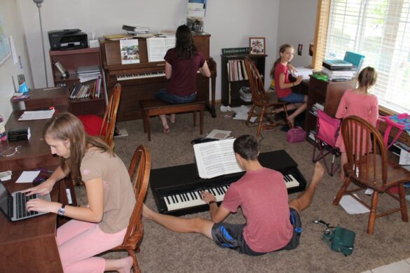 kids work on school and play the pianos in a homeschool classroom