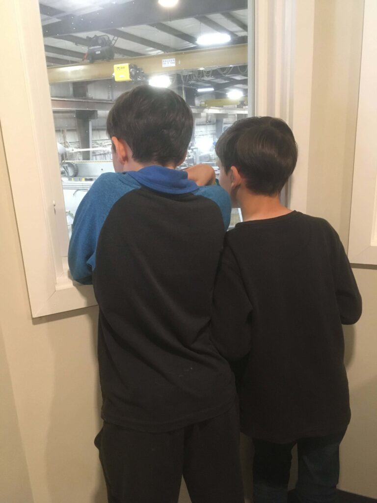 two boys looking out the window into a factory