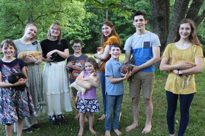 family and sister missionaries hold chickens