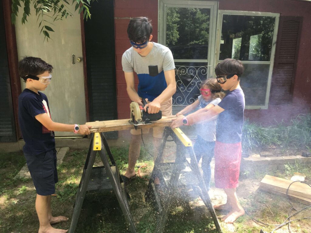 4 kids in a family helping with the table saw