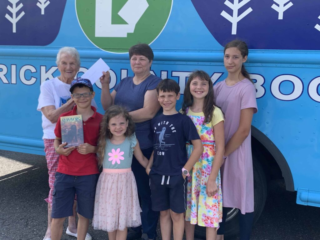 5 children pose in front of the bookmobile with the librarian
