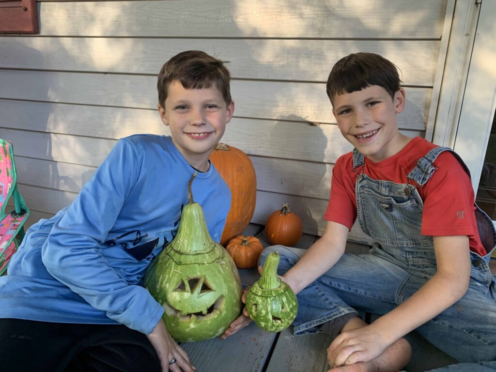 two boys pose with their carved gourds
