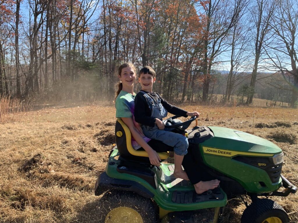 brother and sister riding john deere and mowing